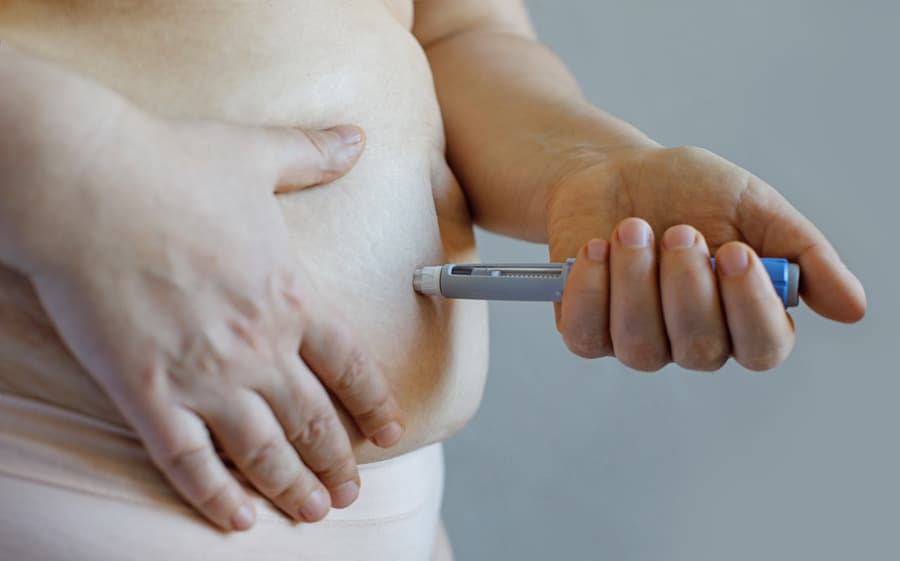 A woman holding an electronic thermometer, checking her tummy temperature.