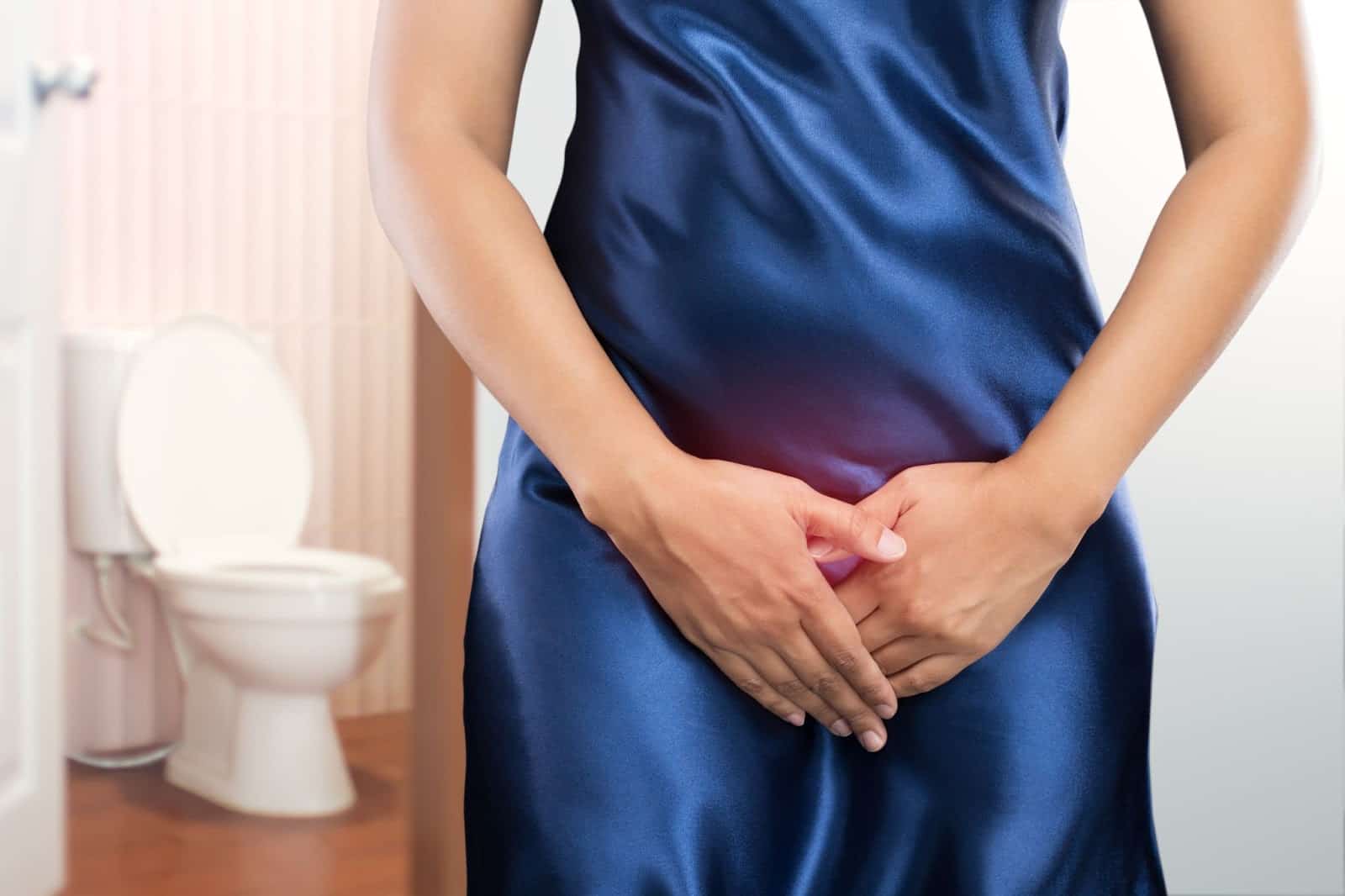 A woman in a blue dress gently holds her stomach, symbolizing comfort and support from the Emsella chair for incontinence treatment.