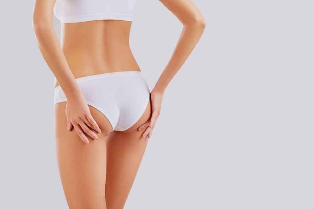 A woman in white underwear poses against a white background, showcasing her enhanced curves and lifted silhouette.