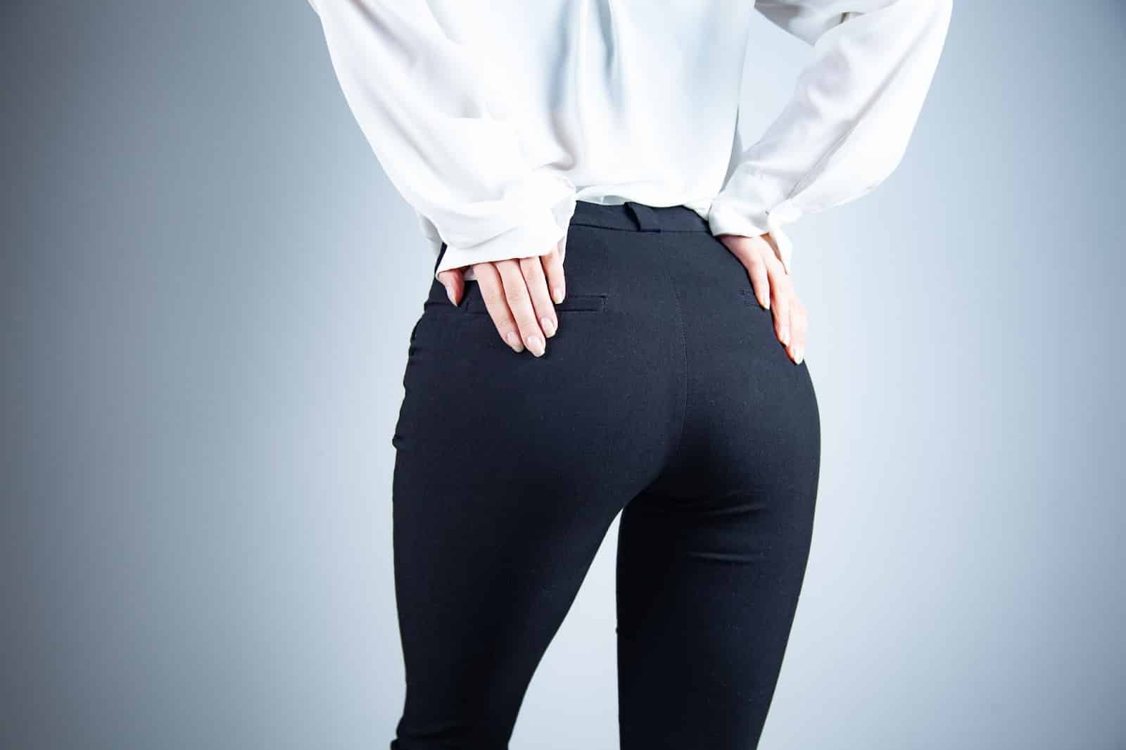 Back view of a woman in black pants, showcasing enhanced curves and a lifted silhouette from butt lift treatments.