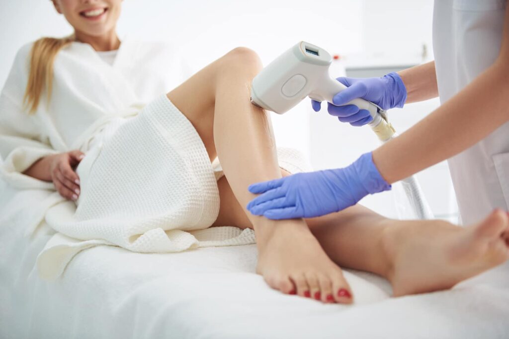 A woman receiving a laser treatment on her leg at Ivee Restorative Care, showcasing advanced skincare technology.