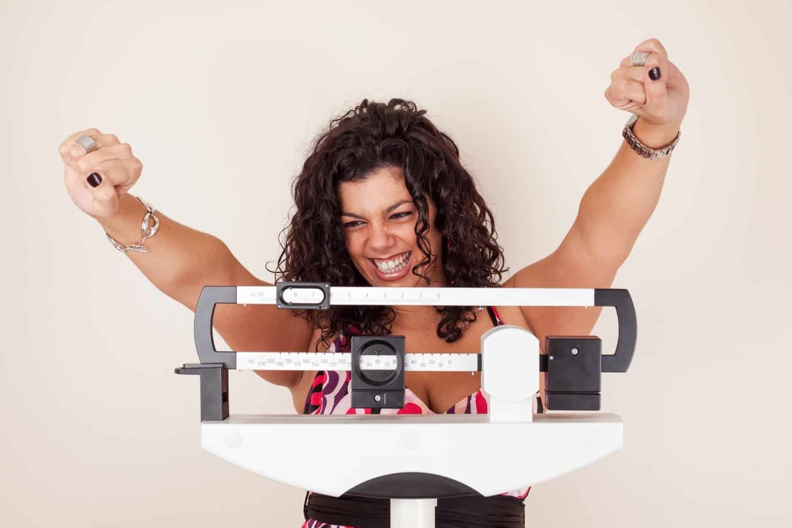 A woman holds a weight scale, symbolizing her journey with Semaglutide as a weight loss solution.